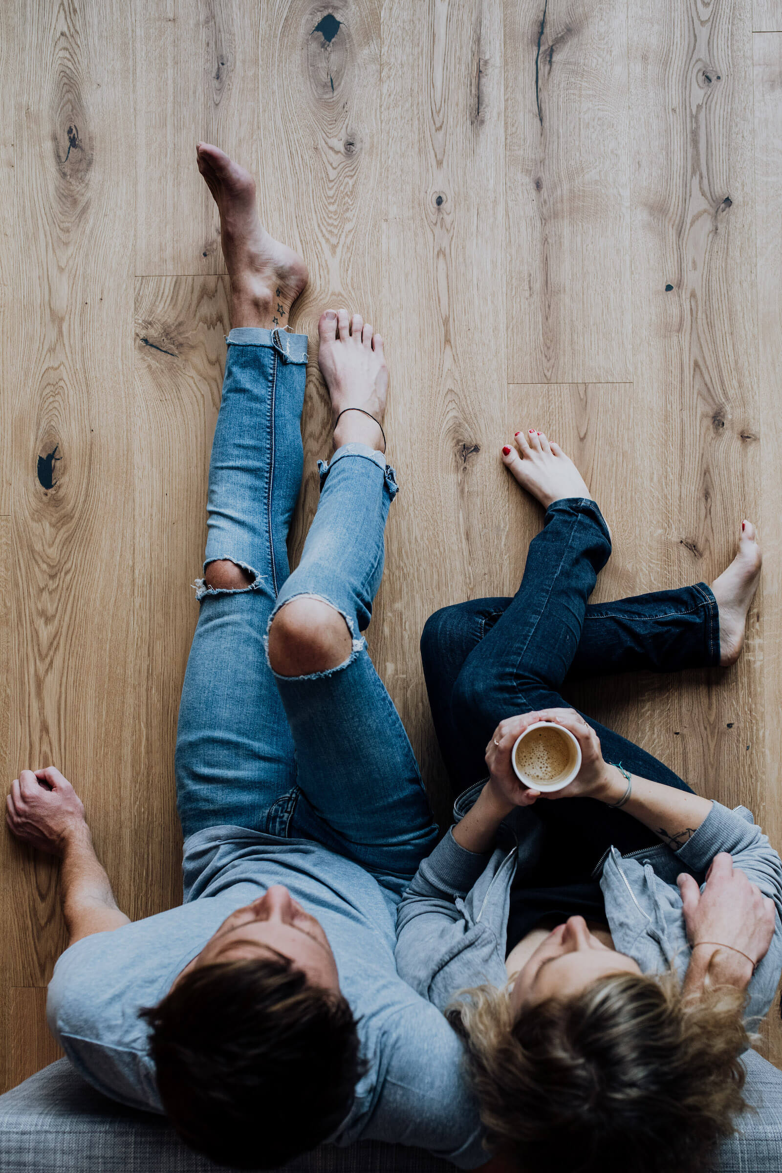 Mann und Frau mit Kaffee auf Parkettboden sitzend