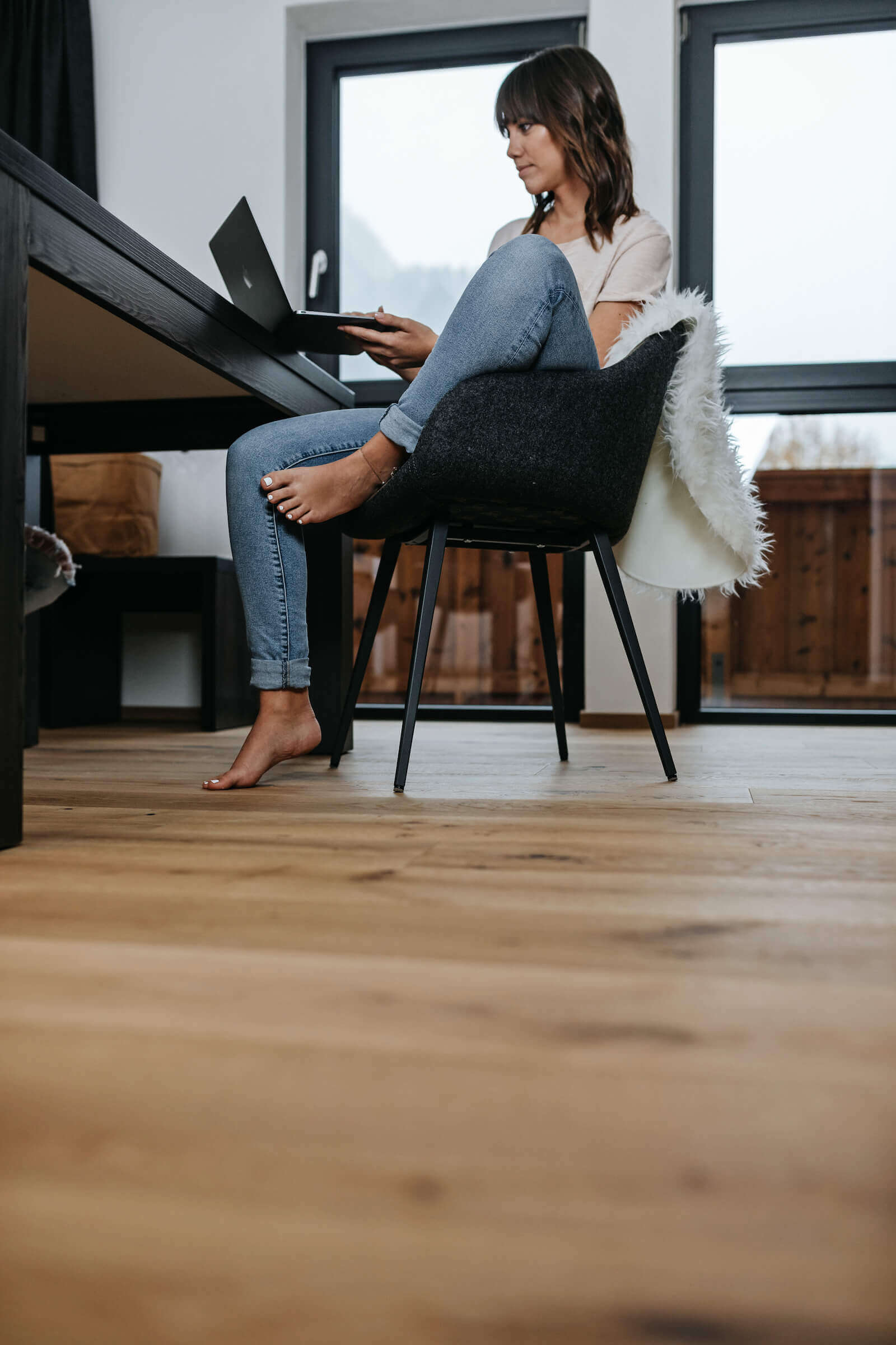 Frau sitzt auf Stuhl mit hochgezogenem Bein