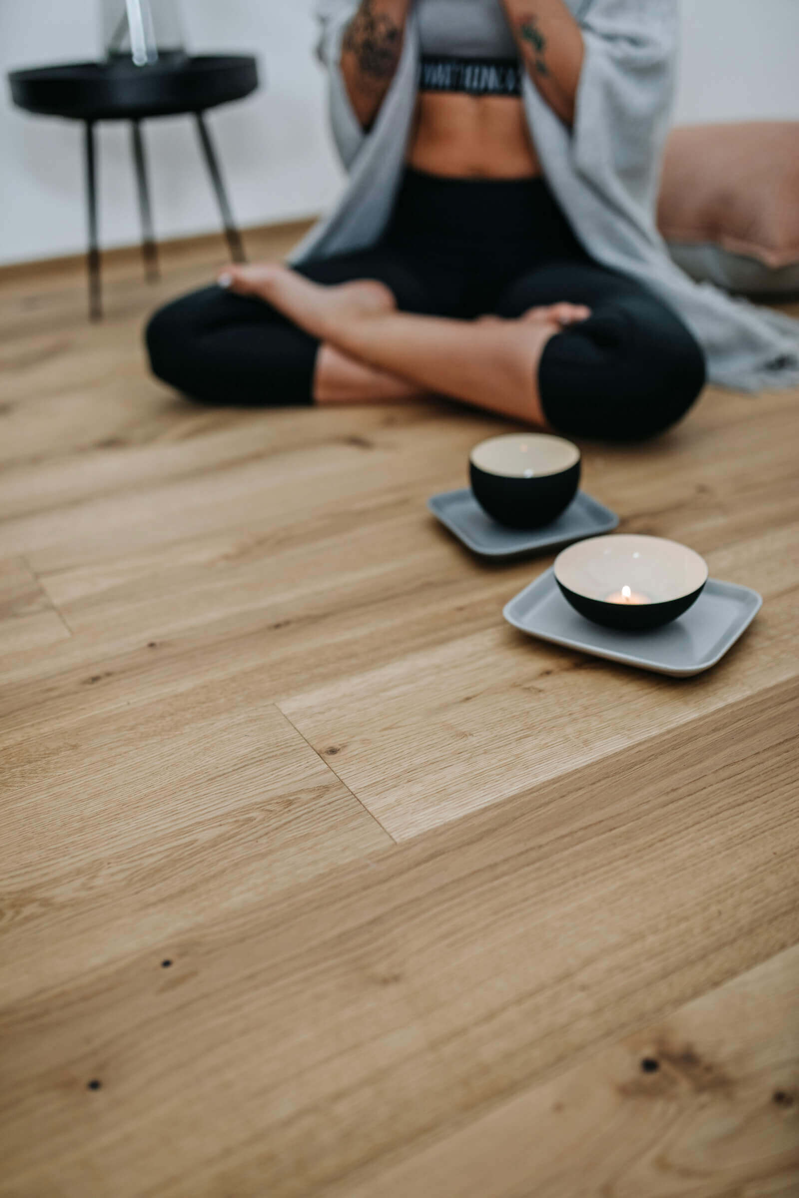 Die Beine einer Frau und Getränketassen auf einem Parkettbocen