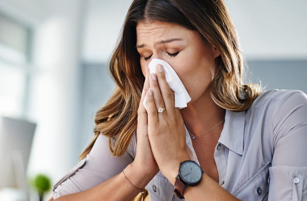 Frau niest in ein Taschentuch wegen einer Allergie